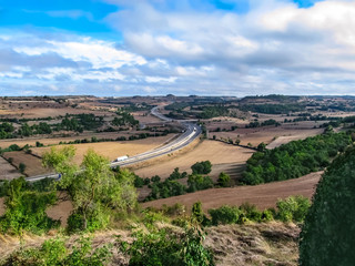 Valley in Catalonia with a zigzag motorway among brown fields. Beautiful autumn scenery of Spain...