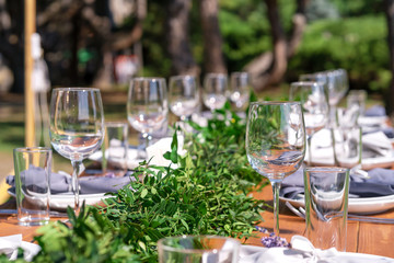 Beautifully decorated wooden table in a summer open-air cafe. Green branch and fresh flowers table decoration