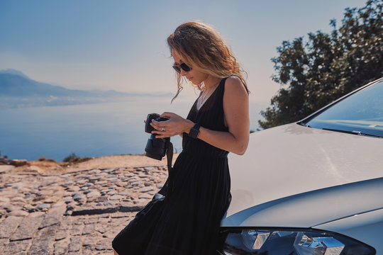 Beautiful woman professional photographer standing with dslr camera near her car while travel in Turkey