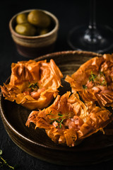 Quiche with smoked salmon on a dark background with a glass of wine