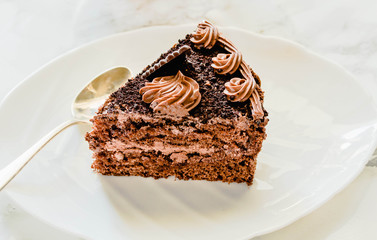 Chocolate cake on a white plate and yellow gold cup of tea. Selective focus