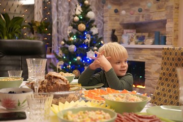 A child of three years in front of the festive table. New Year's holiday table. Salads, meat, alcohol on the New Year's table.