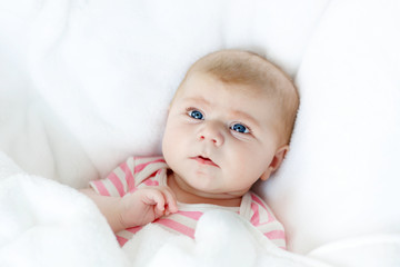 Cute adorable newborn baby in white bed on a blanket. New born child, little adorable girl looking surprised at the camera. Family, new life, childhood, beginning concept