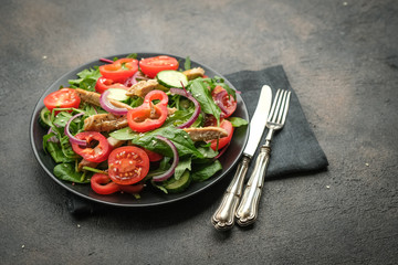 Fresh vegetable salad with chicken meat, herbs and olive oil in a dark plate on a dark background. Healthy food. Top view copy space.