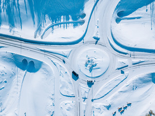 Aerial view of roundabout road intersection with snow winter road with a circular motion