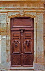 Fototapeta na wymiar An old decorated wooden door with surrounding decorative classical stonework in Provence South of France
