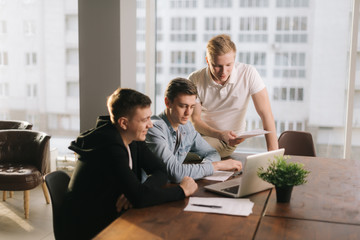 Professional business team of young startupers talk work together share ideas at the table with laptop in creative office. Concept of teamwork young business people.