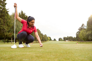 Female Golfer Preparing To Hit Tee Shot Along Fairway With Driver