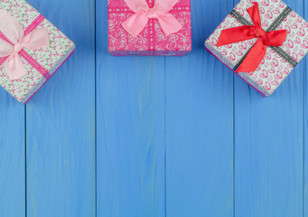 Three gift boxes on bule wooden background. Place the gift box on top so that there is a text box below the greeting.
