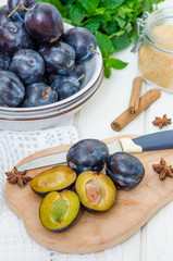 Fresh raw organic plum with jam ingredients on a white wooden background. Vertical orientation.