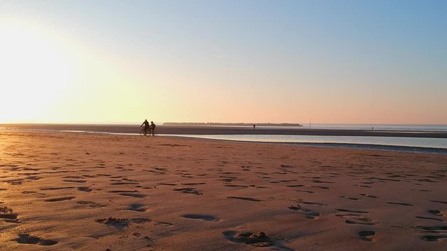 Aerial Drone Shot on North Coast of France, Dunkerque Beach at sunset. 2 bikes on sand. Hauts-de-France, Europe