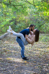 Young beautiful couple in the Park. A man holds a woman in his arms. In the background autumn forest.