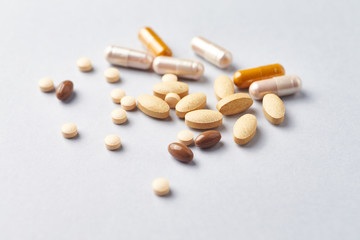 Multicolor vitamins and supplements on bright paper background. Concept for a healthy dietary supplementation. Close up. 
