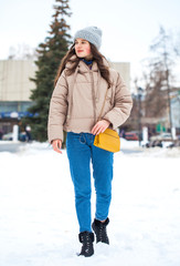 Portrait of young girl in blue jeans walking in a winter park