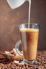  Coffee with cream and brown sugar on a table with coffee beans.