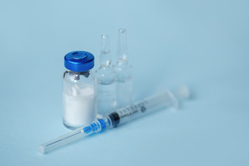 syringe and medicine in glass bottles on a blue background
