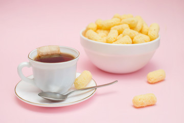 sweet dessert on a pink background, made from corn sticks and a cup of tea