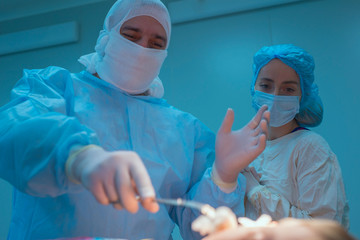 The surgeon and his assistant are a young doctor. The surgeon treats the skin with alcohol before surgery on the childs ear.