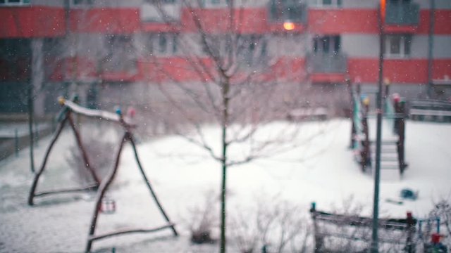 Snow is falling against the background of a playground.