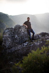 Man on a rock at the mountains with the sun behind