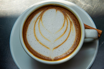 Top view white cup of coffee decorate with cream late art on wooden table in coffee shop
