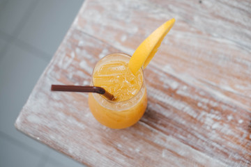 Glass of fresh orange juice and  straw on the wooden table in cafe house.