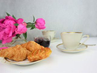 breakfast with two cups of coffee and croissants, bouquet of pink flowers
