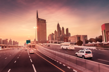 Fototapeta na wymiar High speed highway road at sunset among high skyscrapers in downtown of Dubai city