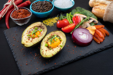 Fried eggs with avocados on the black table with many types of spices