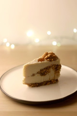 Slice of vegan cake with walnuts, cashew nuts and raisins. Selective focus, bokeh lights.