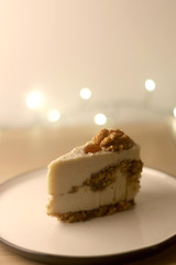 Slice of vegan cake with walnuts, cashew nuts and raisins. Selective focus, bokeh lights.
