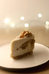 Slice of vegan cake with walnuts, cashew nuts and raisins. Selective focus, bokeh lights.