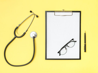 Doctor's desk top view. Stethoscope and notebook on a colored background