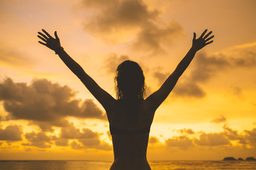 Lady's silhouette with raised arms against sunset