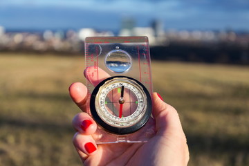 Naklejka premium Female hand holding glass compass, nature in background, sunny autumn day, life change and new years resolutions concept