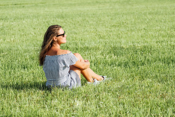 Fototapeta premium Woman wearing dress sitting on green grass field