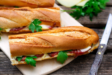 Oven baked baguette sandwich with cheese, ham and tomato