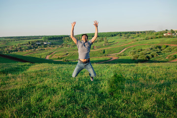 A man in jeans and a T-shirt in a jump. The male is happy and free in nature