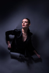 Vogue model posing in little black dress through wrapped paper grey background in studio, dramatic fashion poses, make up and hairstyle