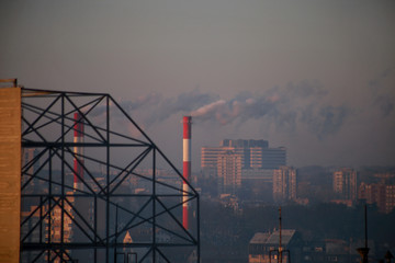Smoking from industrial chimneys of heating plant emits smoke, smog at sunrise in city, pollutants enter atmosphere. Environmental disaster. Harmful emissions, exhaust gases into air. Heating season.