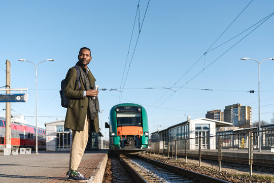 Portrait of stylish man with reusable cup waiting for the train