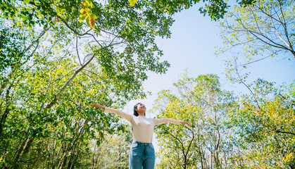 Enjoying the nature. Young beautiful woman arms raised relax and feeling good the fresh air in tropical forest. Freedom concept.