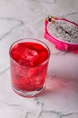 Glass of mango dragonfruit refresher drink on marble table with ice cubes. Copy space.