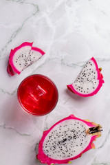 Glass of mango dragonfruit refresher drink on marble table with ice cubes. Copy space.