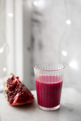 Fresh pomegranate juice in a glass on white marble background