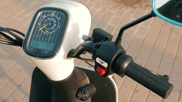 Man hand rider holding handlebar and pressing the start button on motorcycle, man start sharing rental electro scooter