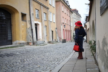 Fototapeta na wymiar Elegant woman in a red hat in the old town of Warsaw.