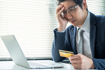 Financial problem concept, asian people feel stressed when seeing excessive expenditure on using his credit card.
