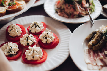 Healthy tasty snacks on plate. Sliced tomatoes with cream cheese and herbs on top. Christmas or New Year banquet.