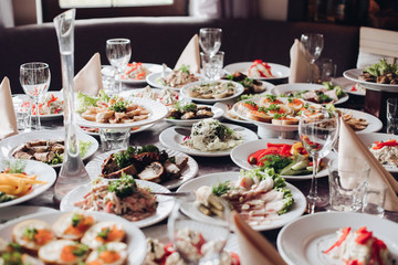 Variety of tasty cold snacks served on white ceramic plates over wedding banquet special occasion...